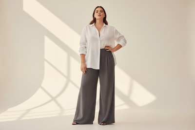 Woman model wearing wide leg trousers. Tinted white background. Plus size model. 